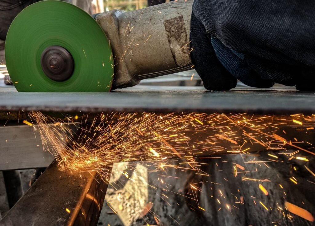 Close-up of a worker using a grinder, creating sparks in a metal workshop environment.